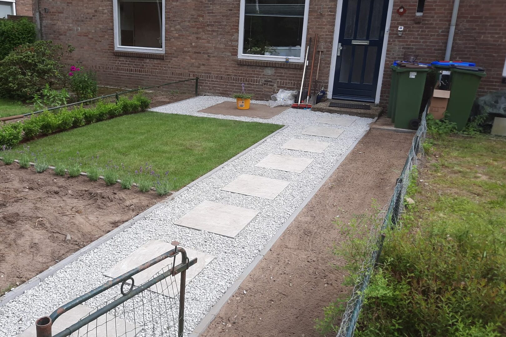 Tuin met grindtegels, border en grasmatten